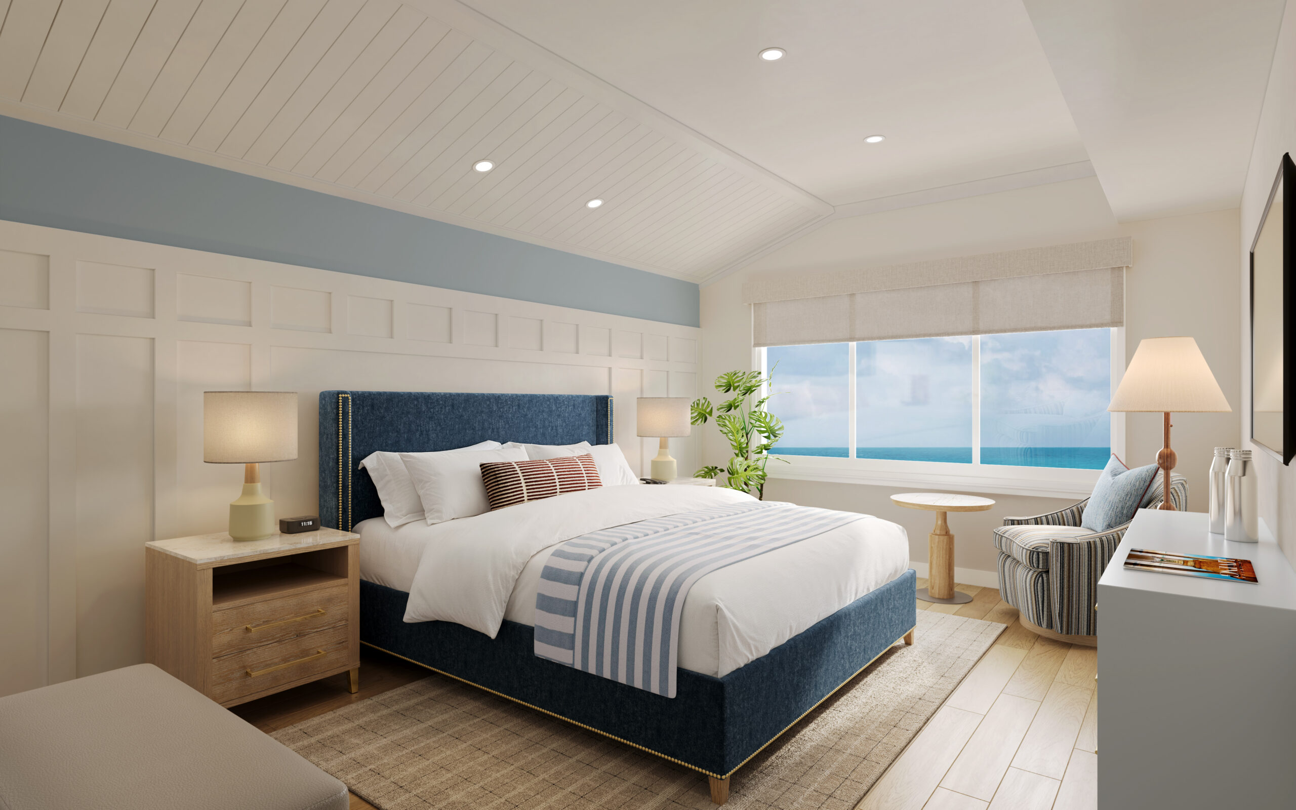 Reimagined bedroom with a deep navy upholstered bed, brass nailhead trim, and ocean view