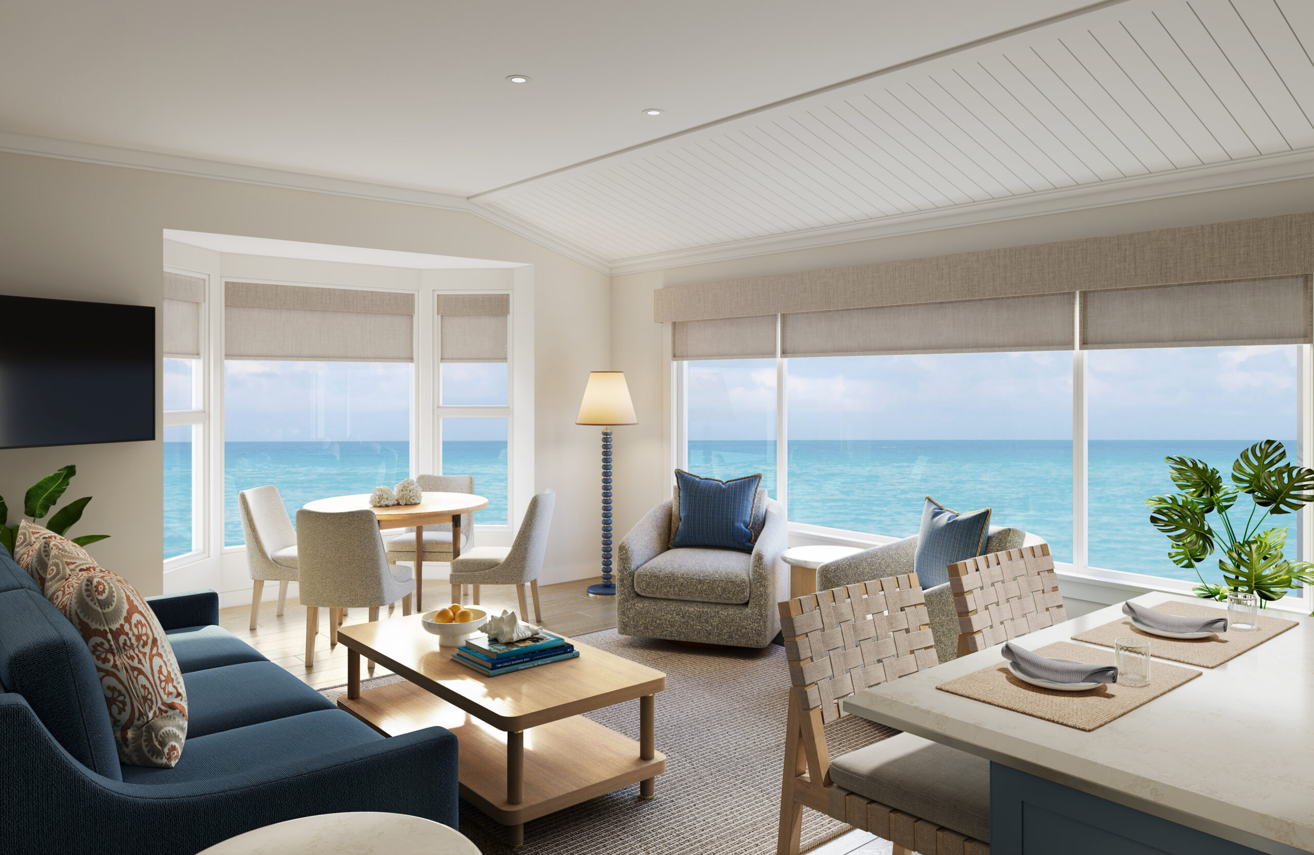 Reimagined living space with a navy sofa, white wainscoting, and floor-to-ceiling ocean views